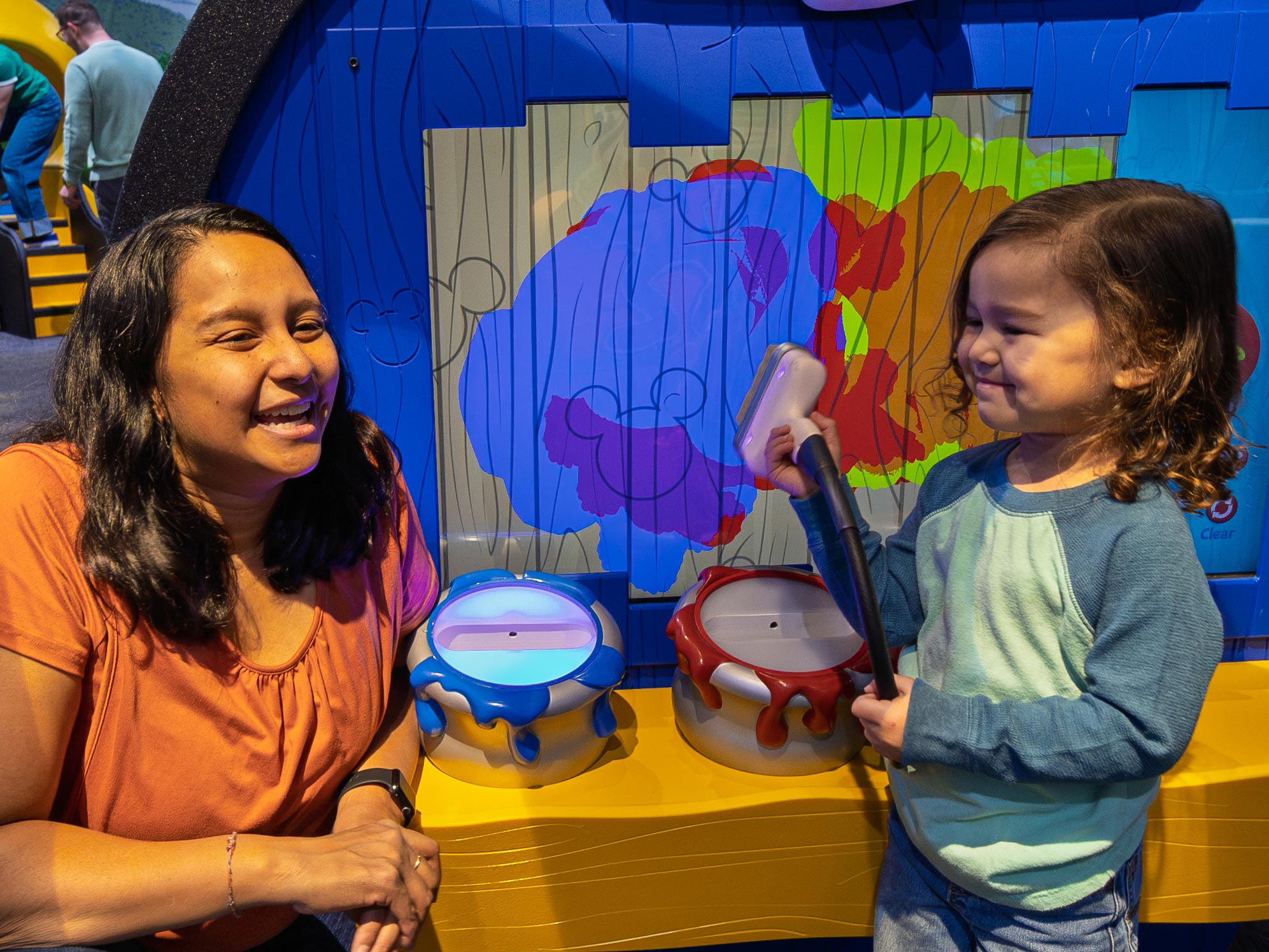 Child and grown-up painting Pluto's doghouse in the exhibit.